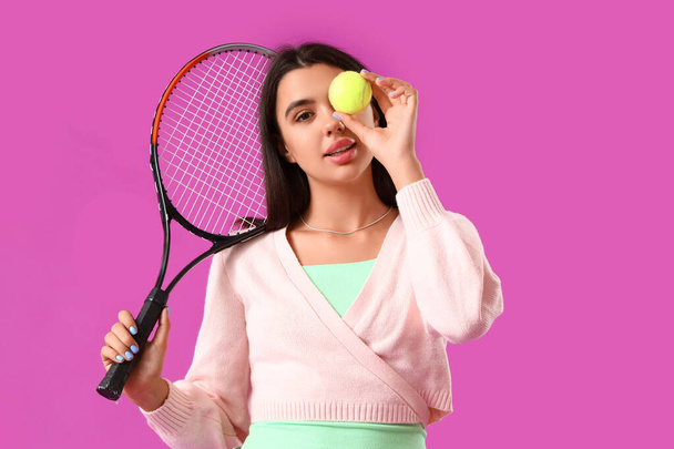 Kaunis nuori nainen tennismaila ja pallo violetti tausta - Valokuva, kuva