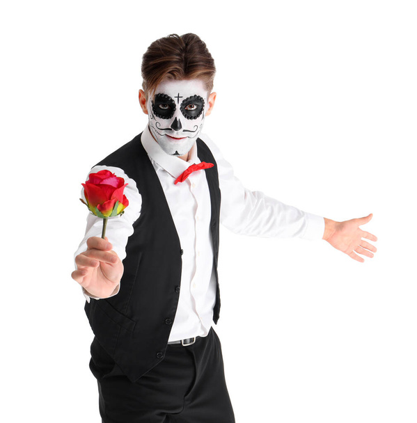 Hombre joven con cráneo pintado y rosa sobre fondo blanco. Celebración del Día de los Muertos (El Día de Muertos) - Foto, Imagen