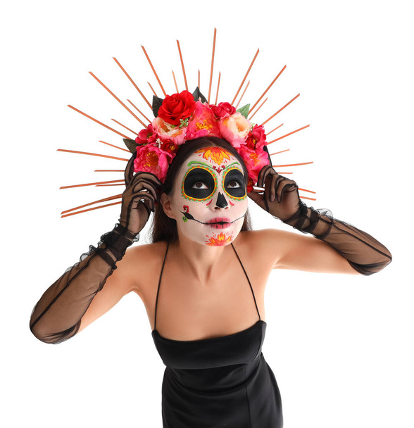 Young woman with painted skull on white background. Mexico's Day of the Dead (El Dia de Muertos) celebration - Photo, Image