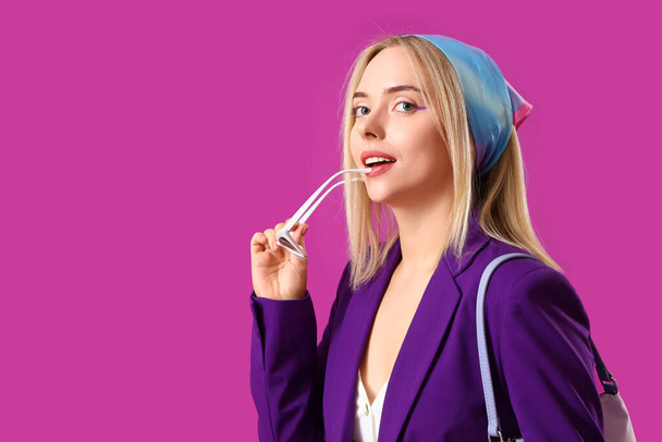 Красивая молодая женщина со стильными аксессуарами на фиолетовом фоне - Фото, изображение