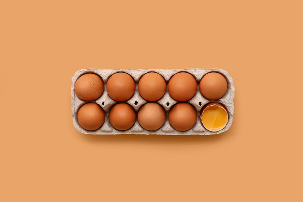 Držák s popraskané a celé kuřecí vejce na béžovém pozadí - Fotografie, Obrázek