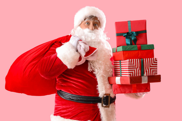 Santa Claus with bag and Christmas gift boxes on pink background - Photo, Image