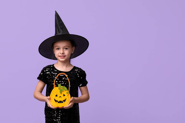 Carino bambina vestita per Halloween come strega con borsa su sfondo viola - Foto, immagini