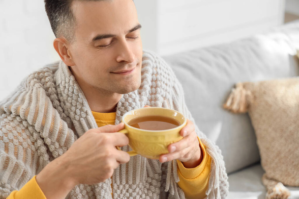 Handsome man with warm plaid and cup of hot tea at home, closeup - Photo, Image