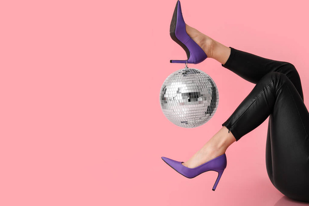 Jambes féminines en talons hauts élégants avec boule disco sur fond rose - Photo, image