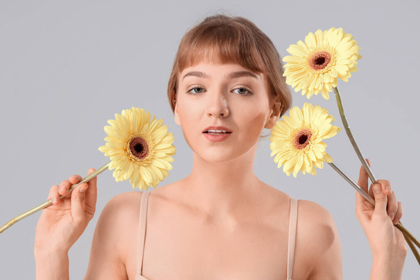 Beautiful young woman with flowers on light background, closeup - Photo, Image