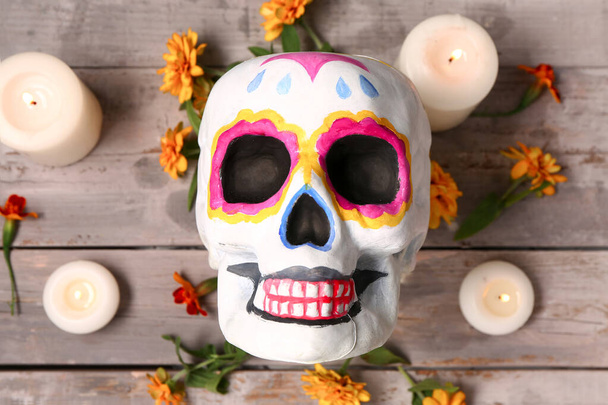Geschilderde schedel met goudsbloem en kaarsen op grijze houten ondergrond. Viering van Mexico 's Dodendag (El Dia de Muertos)) - Foto, afbeelding