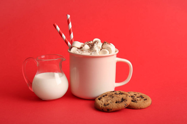 Cup of hot cocoa with marshmallows and sweet cookies on red background - Photo, Image