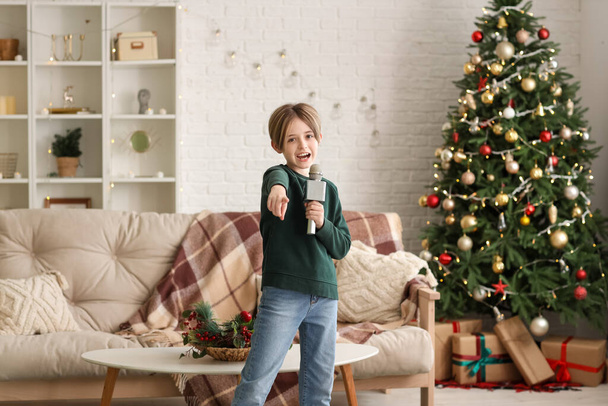 Χαριτωμένο αγοράκι με μικρόφωνο τραγουδά στο σπίτι παραμονή Χριστουγέννων - Φωτογραφία, εικόνα