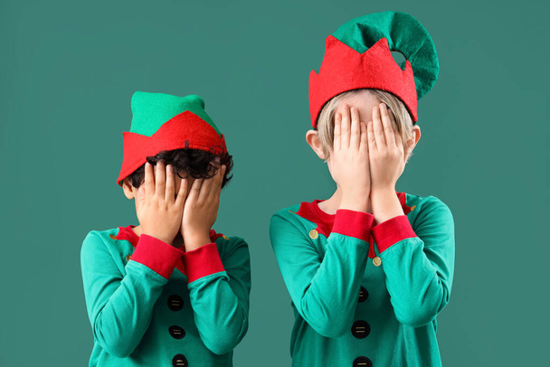 Милые маленькие дети в костюмах эльфов закрывают глаза на зеленом фоне - Фото, изображение