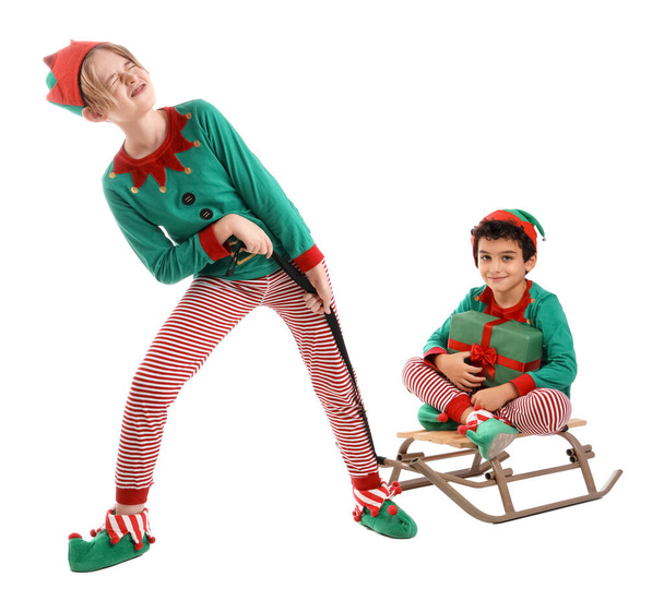 Nette kleine Kinder in Elfenkostümen mit Schlitten und Geschenkbox isoliert auf weißem Hintergrund - Foto, Bild
