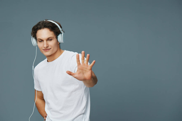Figyelj ember boldog férfi diák érzelem élvezni személy stúdió gúnyolódik fiatal zene póló fel kaukázusi életmód mosoly hang portré fülhallgató szürke hallgatás - Fotó, kép