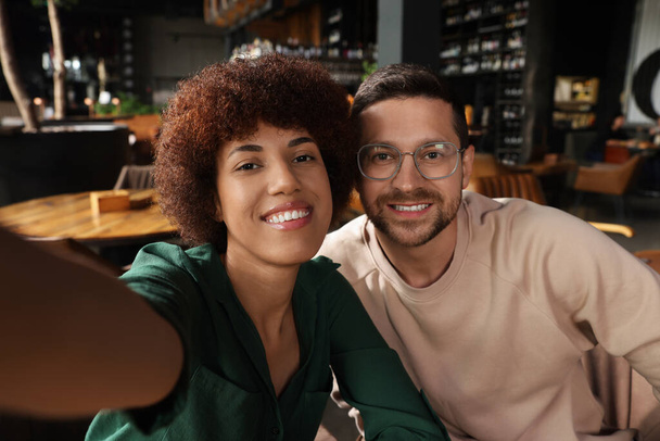 International dating. Happy couple taking selfie in cafe - Фото, зображення