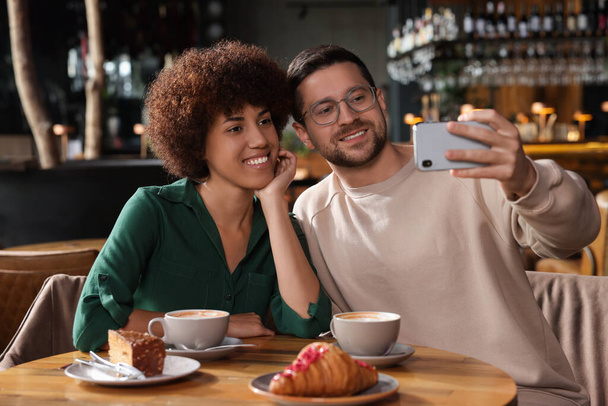 International dating. Happy couple taking selfie in cafe - Fotografie, Obrázek