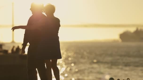 Sylwetka dorosłej pary w podeszłym wieku tańczącej w pobliżu mostu morskiego- duży statek wycieczkowy na tle, wschód słońca - Materiał filmowy, wideo