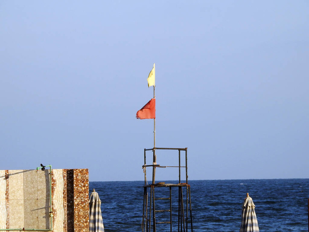 Sárga és piros zászlók a strandon, strand figyelmeztető zászló rendszer, piros zászló azt jelenti, magas kockázat, durva körülmények, erős szörf, és az áramlatok, Sárga zászló azt jelenti, közepes kockázat, könnyű szörf áramlatok, életmentő - Fotó, kép