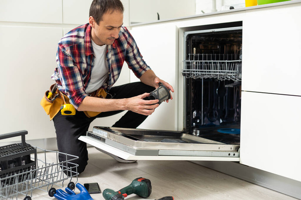 Arbeiter reparieren die Spülmaschine in der Küche. Hochwertiges Foto - Foto, Bild