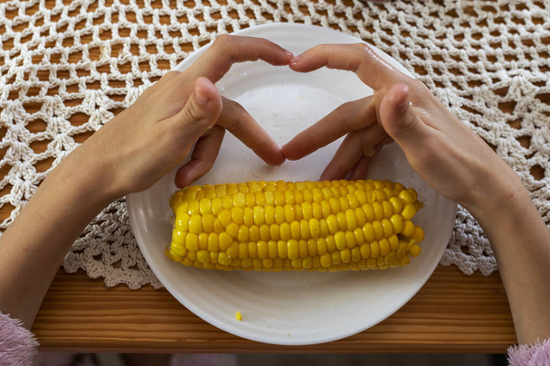 hacer corazones con los dedos delante del maíz - Foto, imagen