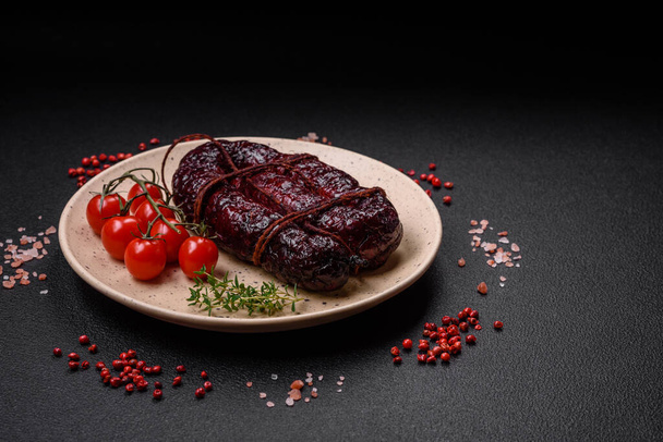 Delicious black blood sausage or black pudding with spices and herbs grilled on a black concrete background - Photo, Image