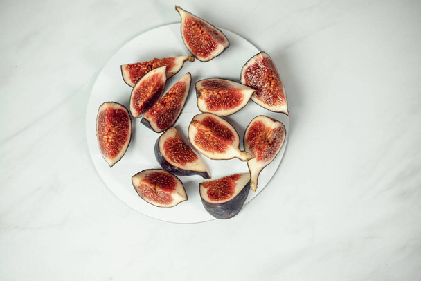 Reife und süße Feigen geschnitten und in einem Teller auf weißem Hintergrund mit freiem Platz angeordnet. Obst und Vegetarismus - Foto, Bild