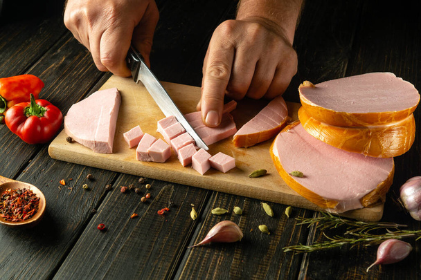 Cortar salchichas escaldadas en tabla de cortar de madera en la cocina doméstica por manos chef para un sándwich. - Foto, Imagen