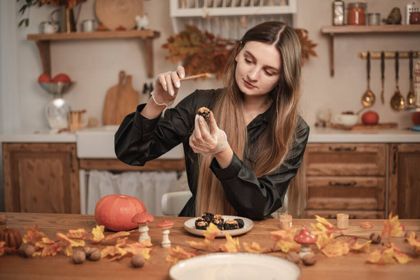 Il pasticcere di donna decora la caramella nella forma di teschi neri per Halloween con oro. Il processo di creazione di caramelle per Halloween - Foto, immagini