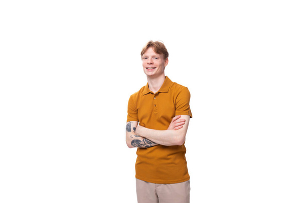 junger, stylischer rothaariger Mann mit Frisur und Tätowierung auf dem Arm trägt ein gelbes T-Shirt. - Foto, Bild