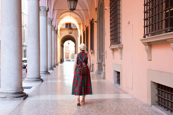 若い女性学生はイタリアのボローニャ市の有名なアーチギャラリーに気軽に立っていた. ボローニャは学生都市であり,世界最古の大学の本拠地です. - 写真・画像