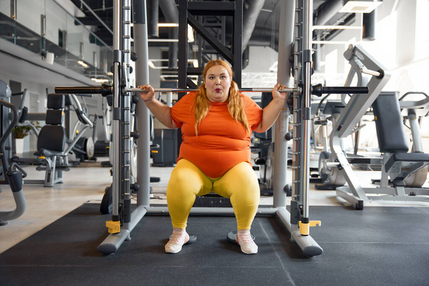 Mladá žena s nadváhou trénink s barbell řádek na hubnutí a sílu čerpání. Osobní sportovní trénink v posilovně - Fotografie, Obrázek