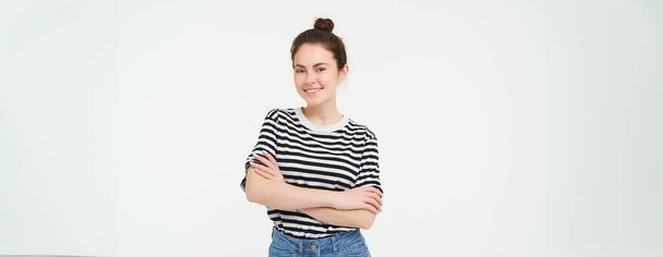 Imagen de una joven carismática en camiseta a rayas y jeans, con un aspecto seguro y feliz, sonriendo a la cámara, emociones sinceras, fondo blanco. - Foto, Imagen