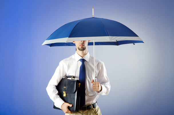 Businessman holding umbrella in the office - Foto, afbeelding