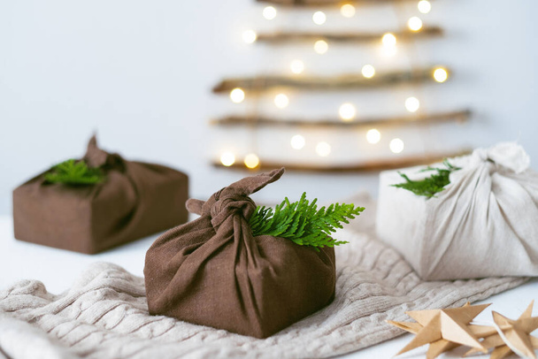 Composición navideña con cajas de regalo, decoración ecológica, conos de pino, luces de árbol de Navidad en el fondo. Eco y Navidad Sostenible. Foto de alta calidad - Foto, Imagen