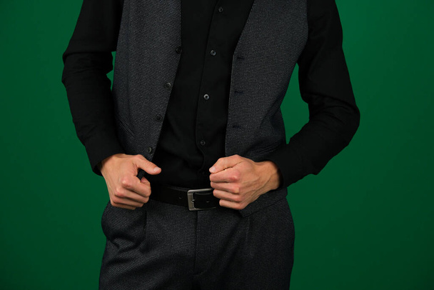 nierozpoznawalne ludzie ręce mężczyzn na kamizelce z trzyczęściowy klasyczny garnitur pasek czarna koszula ciemnoszare ubrania na zielonym tle chromakey krawcowej. gotowy strój - Zdjęcie, obraz