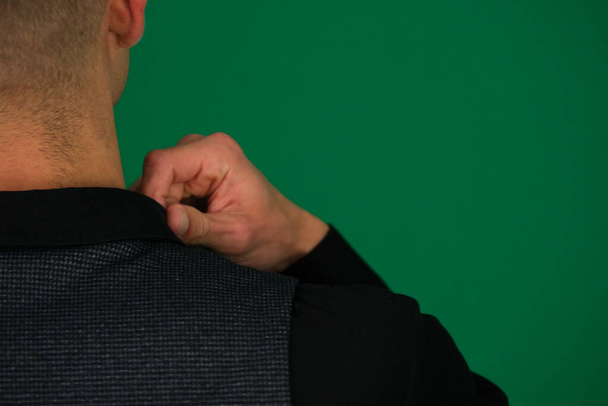close-up de um homem mãos endireitando uma camisa preta, ele dá colete de um terno clássico, ombros de lados diferentes, conjunto Três fotos em um fundo verde chromakey close-up cabelo escuro jovem - Foto, Imagem