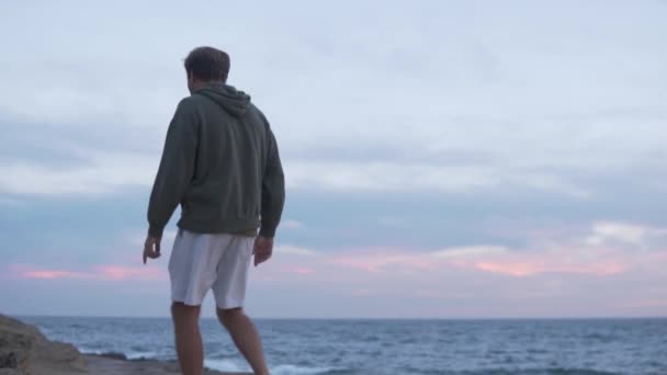 Este egy férfi sétál a tengeren naplementekor.. - Felvétel, videó