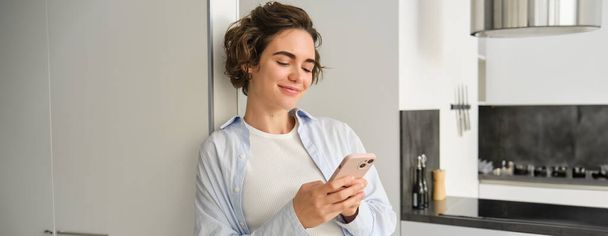 Muotokuva brunette nainen älypuhelin, lähettää viestin, tarkistaa hänen mobiilisovellus, tilaaminen toimitus kotiin. - Valokuva, kuva