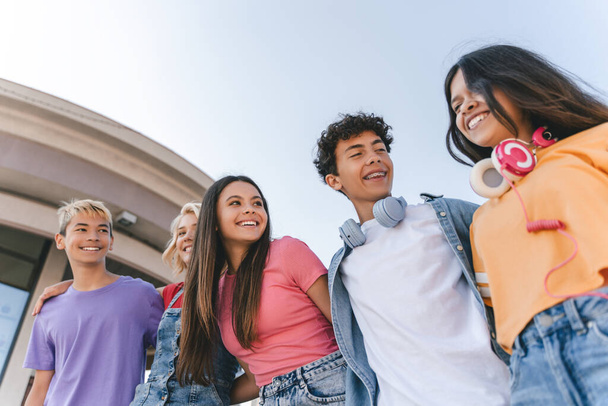 Group of smiling friends, multiracial teenagers wearing colorful casual clothes talking, walking on the street. Happy stylish boys and girls outdoors. Friendship, positive lifestyle, diversity  - Photo, Image