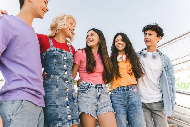 Group of smiling friends embracing, talking, walking on the street. Happy stylish boys and girls outdoors. Friendship, positive lifestyle, diversity  - Photo, Image