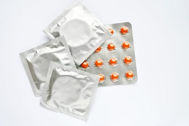 drei Kondome und Antibabypillen isoliert auf weiß - Foto, Bild