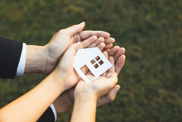 Biznesmen trzymać ikonę domu wraz z dziećmi strony, przedstawiając możliwości kredytu mieszkaniowego w ramach sprzedaży nieruchomości. Promowanie inteligentnych ekologicznie domów, uosabianie wizji zrównoważonej przyszłości. Żywica - Zdjęcie, obraz