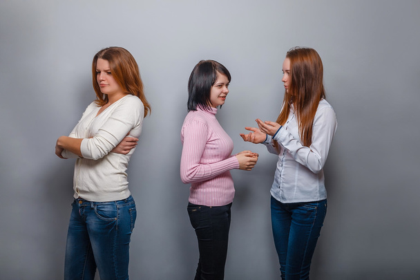 Две девушки говорят блондинка европейский внешний вид и игнорировать третью девушку на сером фоне, обида, грусть конфликта друг
 - Фото, изображение