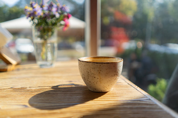Чашка белого кофе на деревянном столе в кафе с подсветкой - Фото, изображение