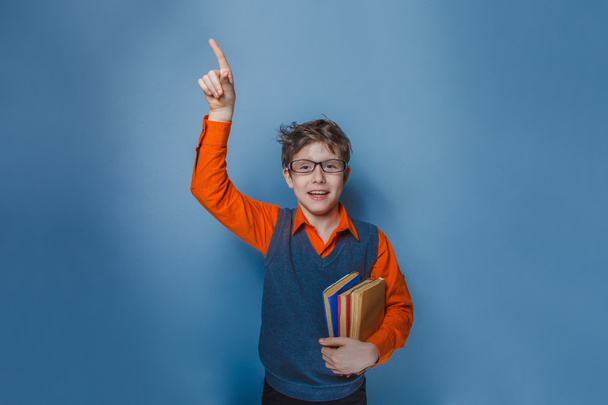 Garçon européen de dix ans dans des lunettes pouces levés, l'idée du livre sur un fond bleu
 - Photo, image