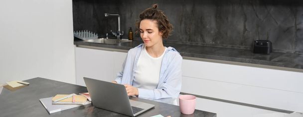Retrato de 25 años mujer, estudios en línea, relojes curso en internet, trabaja en el ordenador portátil desde su casa. - Foto, Imagen