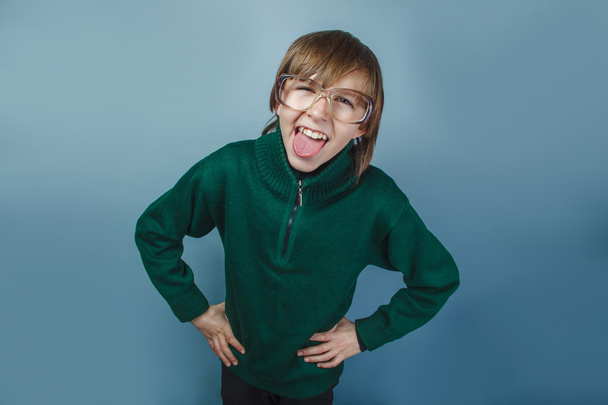Euroopan näköinen poika kymmenen vuotta osoittaa kielen kiusaa sinisellä taustalla
 - Valokuva, kuva