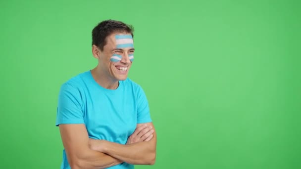 Wideo w studiu z chromą szczęśliwego mężczyzny z pomalowaną na twarzy argentyńską flagą spoglądającego w pustą przestrzeń kopiowania - Materiał filmowy, wideo