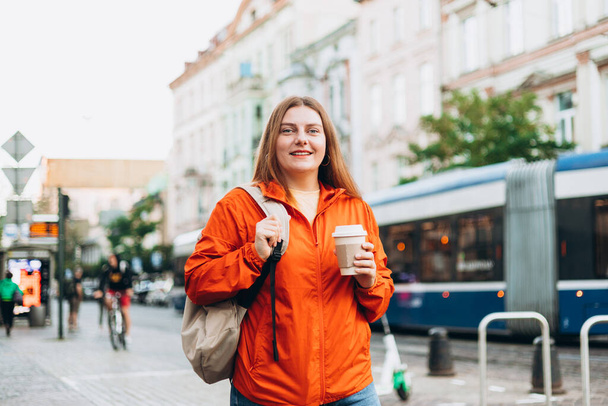 Молодая красивая женщина с кофе ходит по улице. Концепция вывоза или доставки. Копирование пространства - Фото, изображение