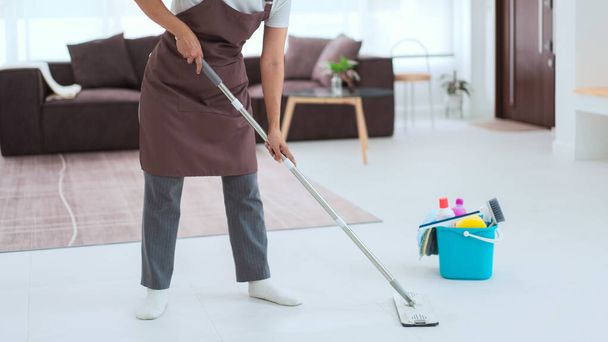 Piika käyttää puhtaampia laitteita ämpäri muovi ja moppi moppaus ja puhdistus pölyä lattialla. - Valokuva, kuva
