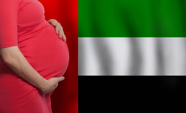 ОАЭ беременная женщина на фоне флага Объединенных Арабских Эмиратов - Фото, изображение