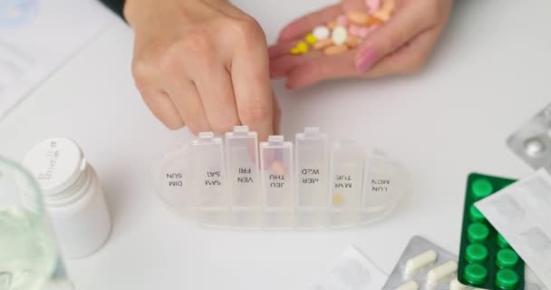 Mujer mano poner pastillas en organizador píldora abierta o pillbox plástico. Clasificación de tabletas para uso diario según prescripción médica - Metraje, vídeo